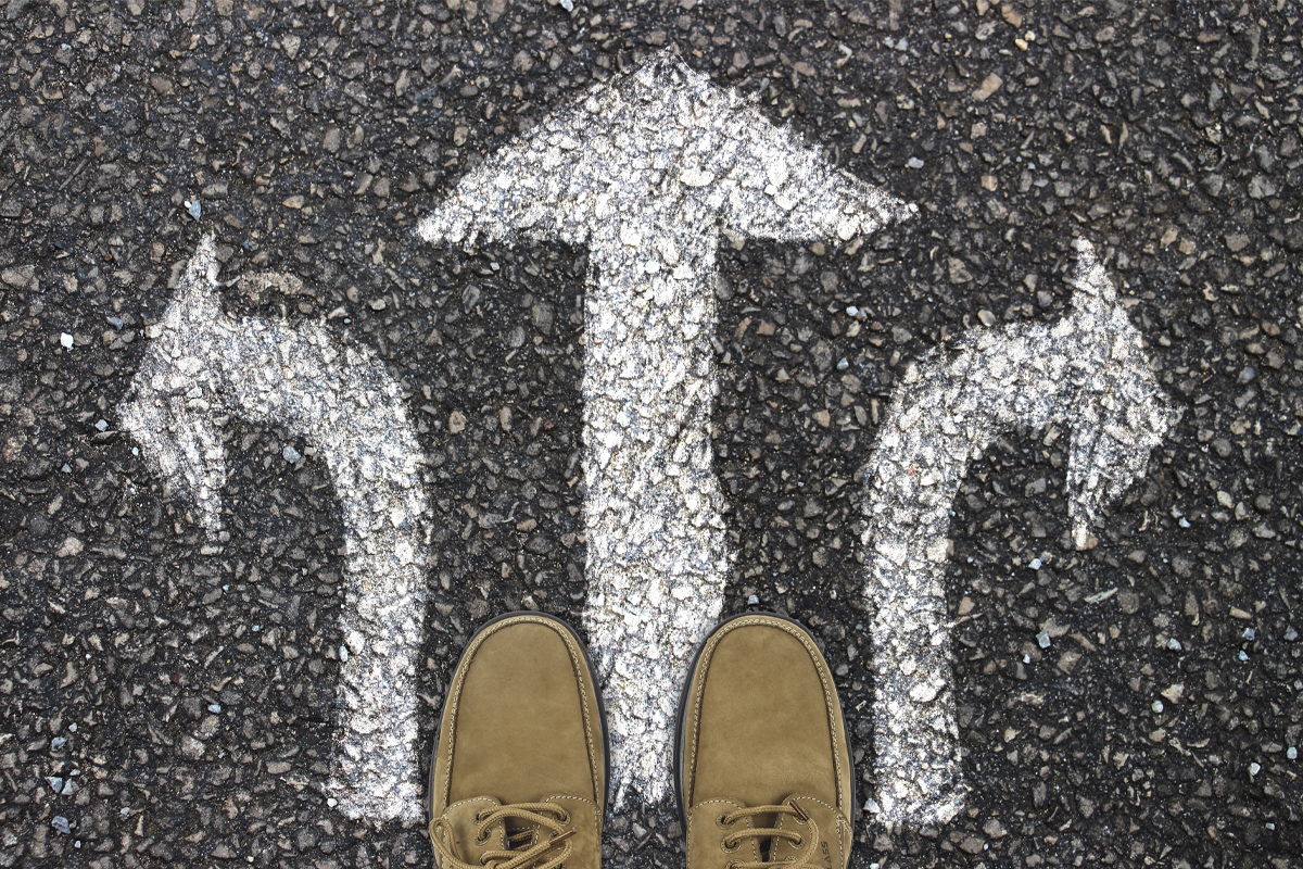 closeup of feet on pavement with arrows in different directions painted on it