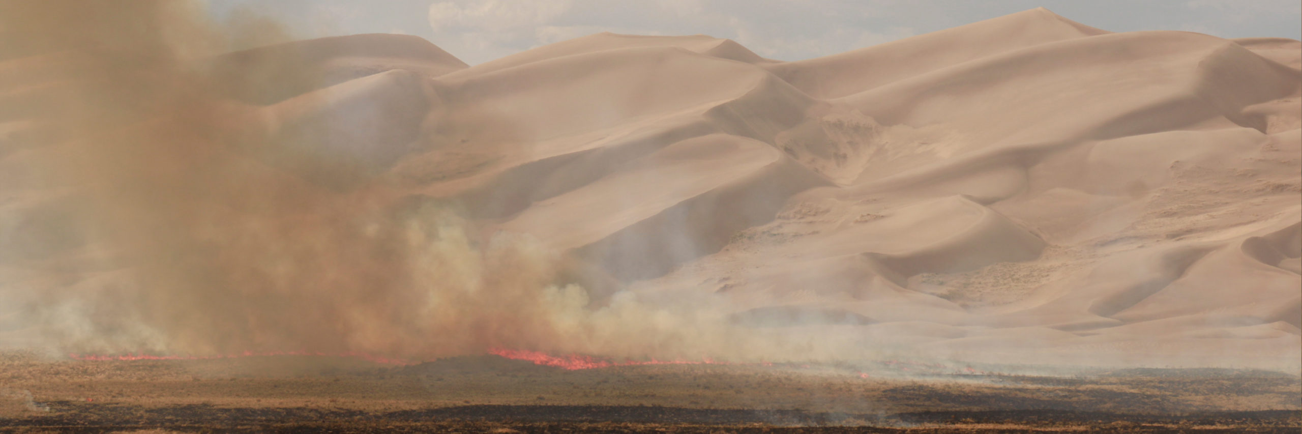 fire and smoke with the Sand Dunes visible in the background