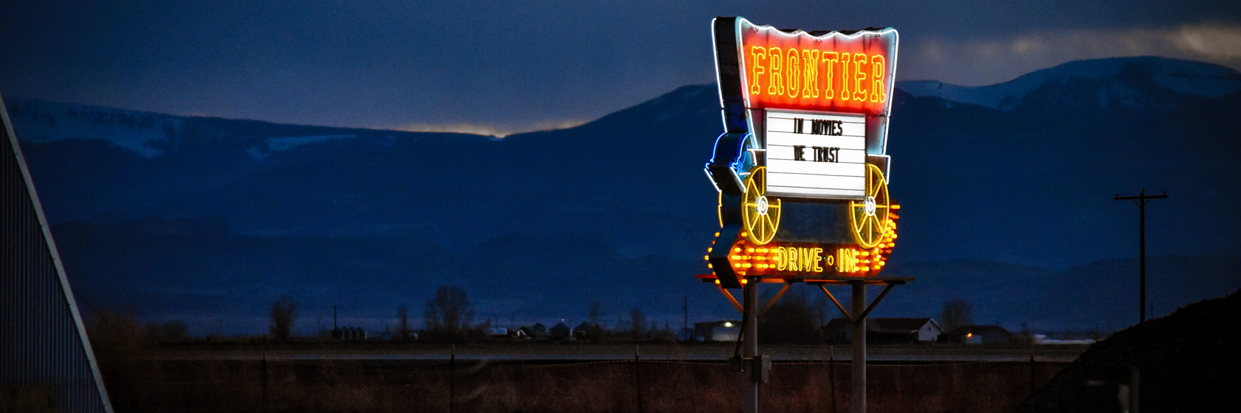 Neon Frontier Drive In sign shot at twilight, with mountains in the background